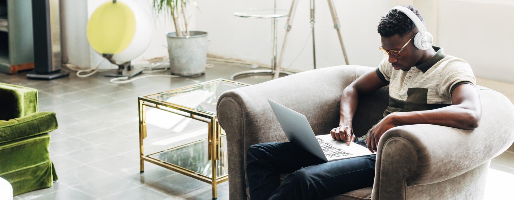 a man sitting on a couch using a laptop